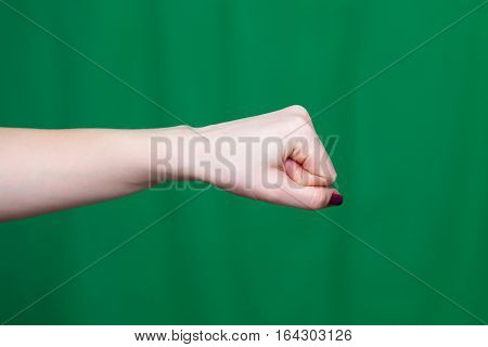 Hand female fist closeup on a green background