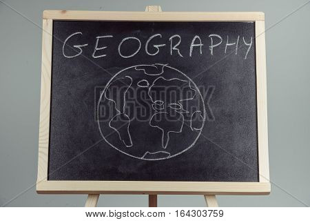 Geography Lesson On Blackboard Or Chalkboard. Written In White Chalk