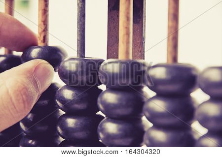 close up image of hand accounting with old abacus. financial concept