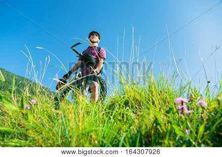 Senior with mountain bike standing at top of a hill, enjoying the view.