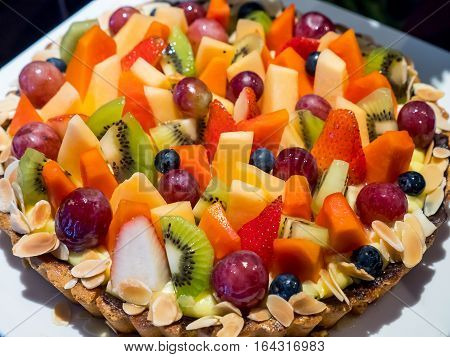 Closeup of sweet dessert mix fruit cake (kiwi cantaloupe blueberry blackberry strawberry grape papaya) selective focus