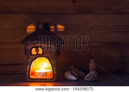 Candle with sea shells on wooden background