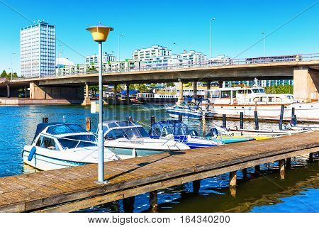 Scenic summer view of pier with bridge architecture and docked motor boats in Hakaniemi District in Helsinki, Finland