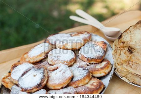 cheesecake and pancakes on the wooden table. Rural food. Food background. Picnic with dairy products and pancakes.