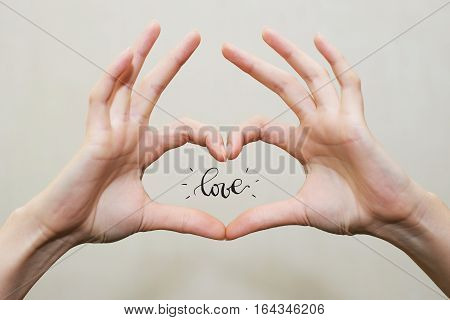 Fingers in heart shape. Love word inside