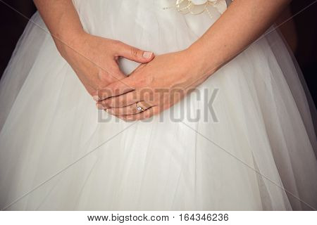 Bride hands on wedding dress with a ring