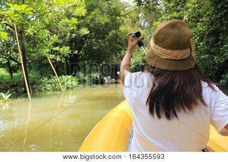 Woman kayaking along a beautiful tropical jungle river. Lots of copy space above and view from behind
