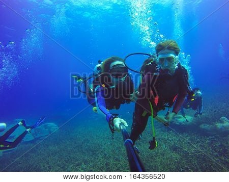 Underwater couple scuba diving selfie shot with selfie stick. Deep blue sea. Wide angle shot.