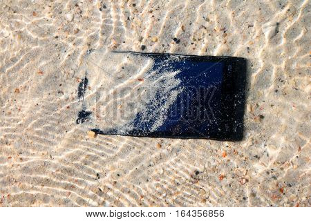 The Phone camera fall to the water on the beach.