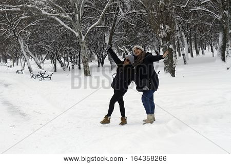 BUCHAREST ROMANIA - January 07 2017: Joyful young women are posing for a picture on a winter day in a central park during the vacation.