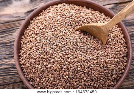 standing on a wooden background earthenware dish with raw buckwheat