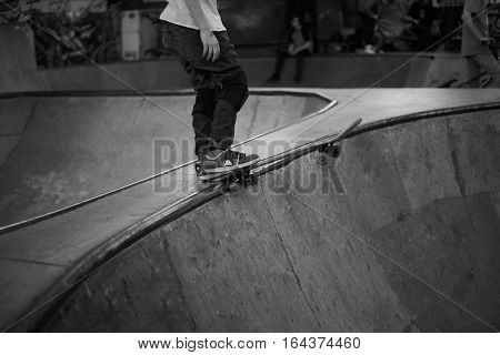 Skateboard and legs of skateboarder in covered park in winter period oer bad weather. Man start trick.