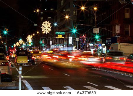 Cars driving in New York City on New Years Eve. Blurred lights and Christmas Ornaments hanging from above