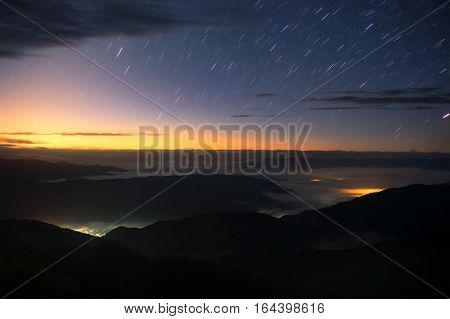 Star trails over twilight sky in morning with sea of cloud view from 1715 view point on  Doi Phukha in Nan province, Thailand.