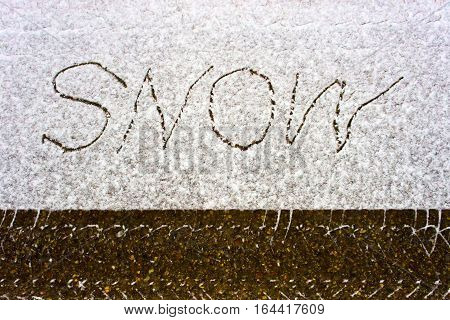 Car track in fresh snow and the inscription SNOW