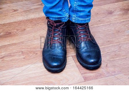 Legs mens in jeans and boots on the parquet floor