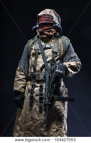 Nuclear post apocalypse life after doomsday concept. Scary closed face of survivor with homemade weapons. Studio closeup portrait on black background