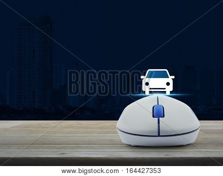 Wireless computer mouse with car front view flat icon on wooden table over city tower Internet service car concept