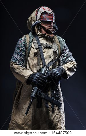 Nuclear post apocalypse life after doomsday concept. Scary closed face of survivor with homemade weapons. Studio closeup portrait on black background