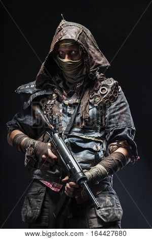 Nuclear post apocalypse life after doomsday concept. Grimy survivor with homemade weapons. Studio closeup portrait on black background