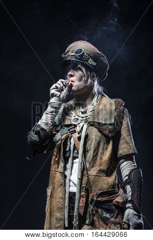 Nuclear post apocalypse life after doomsday concept. Grimy female survivor smoking. Studio closeup portrait on white background