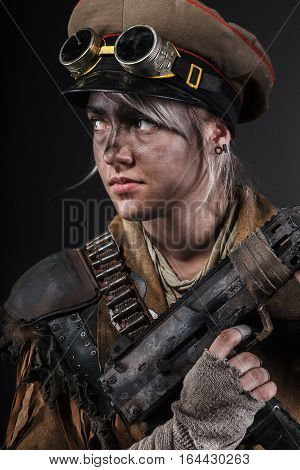 Nuclear post apocalypse life after doomsday concept. Grimy female survivor with homemade weapons. Studio portrait on black background