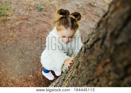 Cute little girl is playing hide and seek outdoors