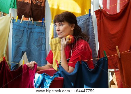 Woman with red apple among the drying clothes