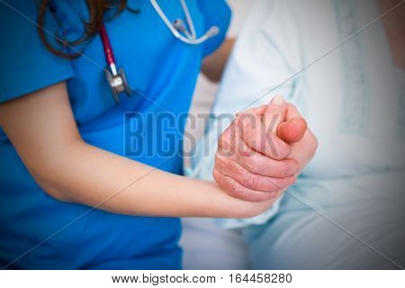 Doctor holding elderly pateient's hands supporting her in hardships.