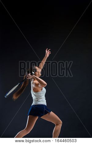 Portrait of beautiful girl tennis player with a racket on dark studio background