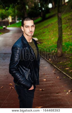 Portrait of a beautiful young boy outdoors in a park. Trees and path in autumn winter.