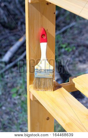 Paintbrush stands vertical on a painted wooden shelving surface. Photo closeup