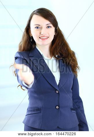 A beautiful young business woman happy and smiling with an open hand ready to seal a deal or saying welcome.the photo has ruscoe space for your text
