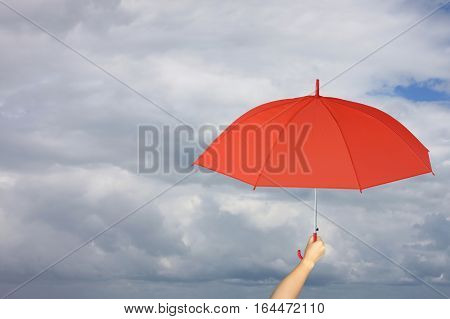 Red umbrella in hand and rain protectionconcept for management business idea on rain cloud background.