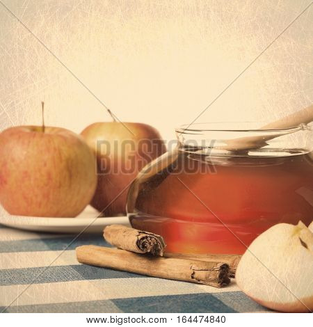 Honey in a jar, cinammon sticks and apples