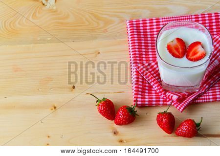 Yogurt and Strawberry in a glass cup on a red tablecloth. On the background of wood. heart in yogurt with valentine 's day.
