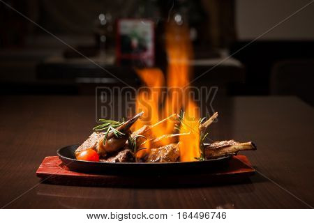 Juicy roasted Prime rib with herbs under fire on a wooden table