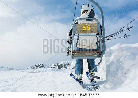 Back view of skier riding a lift. Skking in the mountains.