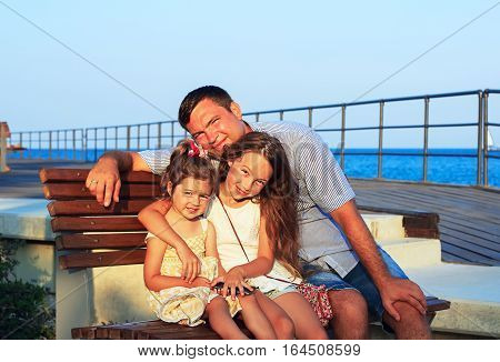 Father and Daughters Playing Together at the Beach at Sunset. Happy Fun Smiling Lifestyle. Dad with his Little Girls spending quality time Together Outdoors