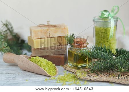 Natural sea salt and handmade soap with branch of pine on white wooden background. SPA concept.
