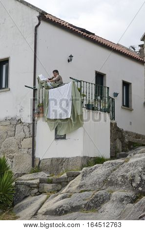 COMBARRO, SPAIN - AUGUST 4, 2016: Woman hanging clothes on the terrace of a house in Combarro a village of the province of Pontevedra in the Galicia region of Spain.