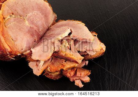 Roasted ham bacon meat joint on a stone slate background