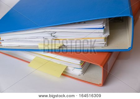 A orange and a blue binder isolated with documents.