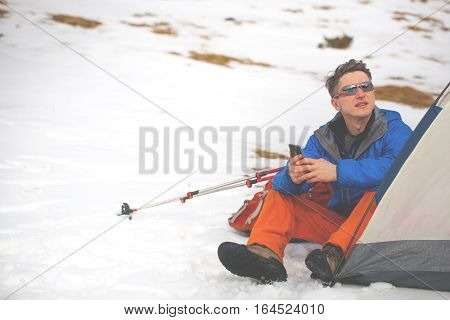 A Man Sits In A Tent In The Winter.