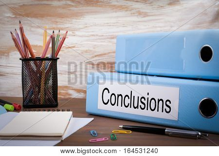 Conclusions, Office Binder on Wooden Desk. On the table colored pencils, pen, notebook paper.