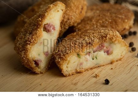 Pille of crispy homemade baked fast food potatoes nuggets with chicken shrimp and cheese on a wooden background.ceramic teapot Top view