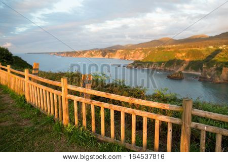Fragment of a rural fence at sunset. On the high rocky ocean coast summer evening a fence is lit with the setting sun focus on a fence