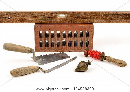 Old construction accessories trowel bricks plummet and level on white background.