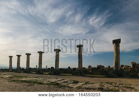Seven columns at Volubilis on a sunny day with blue sky and few clouds , Morocco.