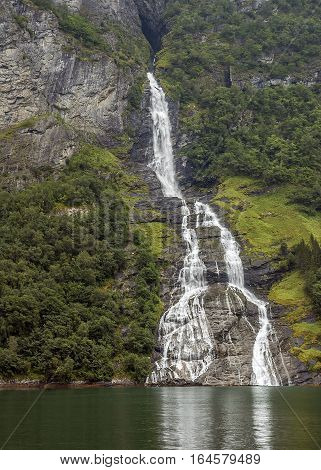 Norway Geiranger fjord. On the banks are located cliffs up to 1400 meters with flowing waterfalls and glaciers. Foggy morning.